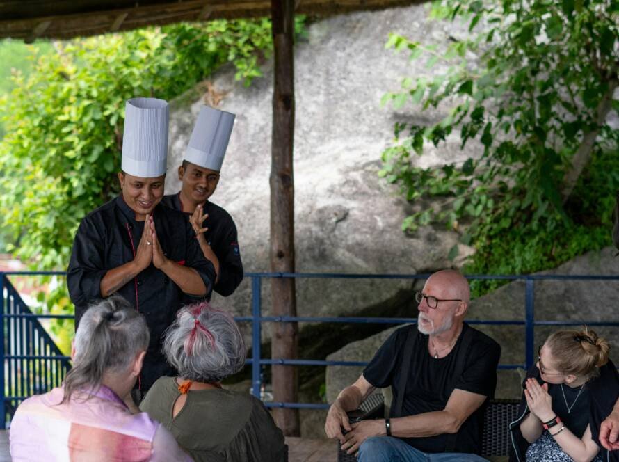 Chefs warmly greeting guests in an open-air resort setting, representing authentic hospitality and local hotel brand identity